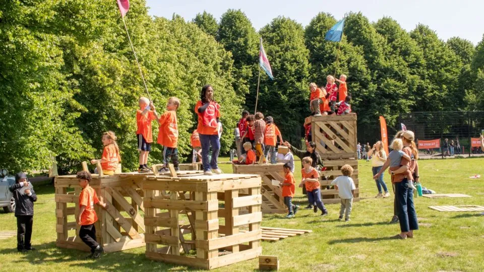 Kinderen spelen buiten tijdens de Buitenspeeldag in Breda op houten speeltoestellen in het park