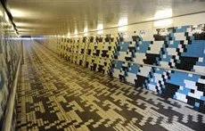 Kunstenaar Peter Struycken voorzag de reizi- gerstunnel van het derde Bredase station van een vloer en hij bekleedde de wanden met een abstract en kleurrijk tegelpatroon.